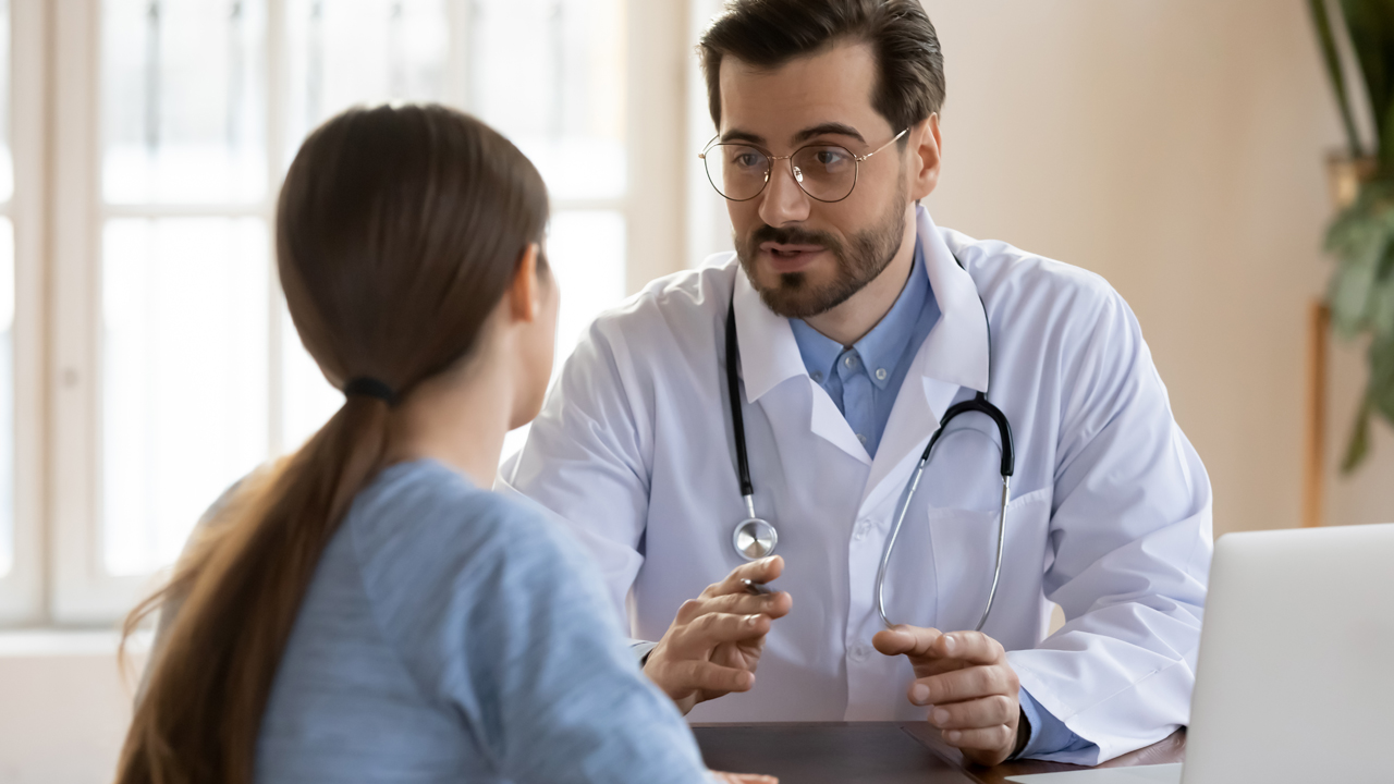 doctor in lab coat with stethoscope discusses teh weight loss plan with a new client